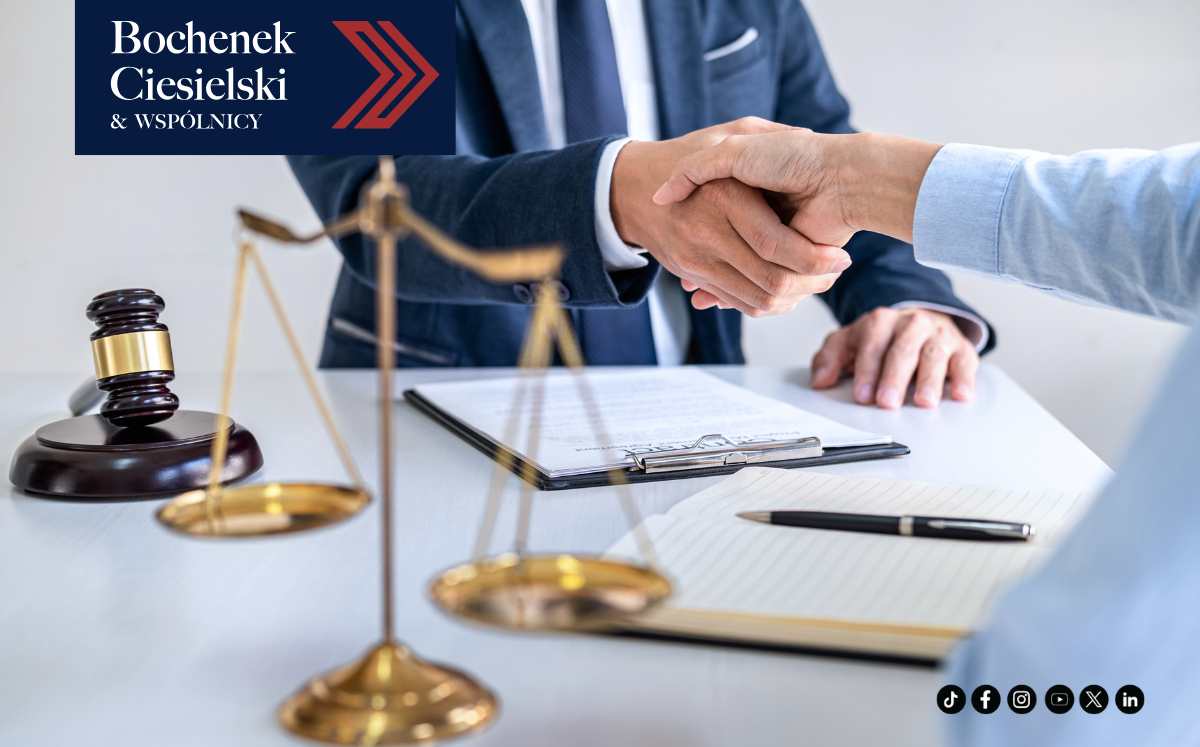 Uścisk dłoni między prawnikiem a klientem przy stole z dokumentami, młotkiem sędziowskim i wagą sprawiedliwości – symbol zakończonej sprawy frankowej.