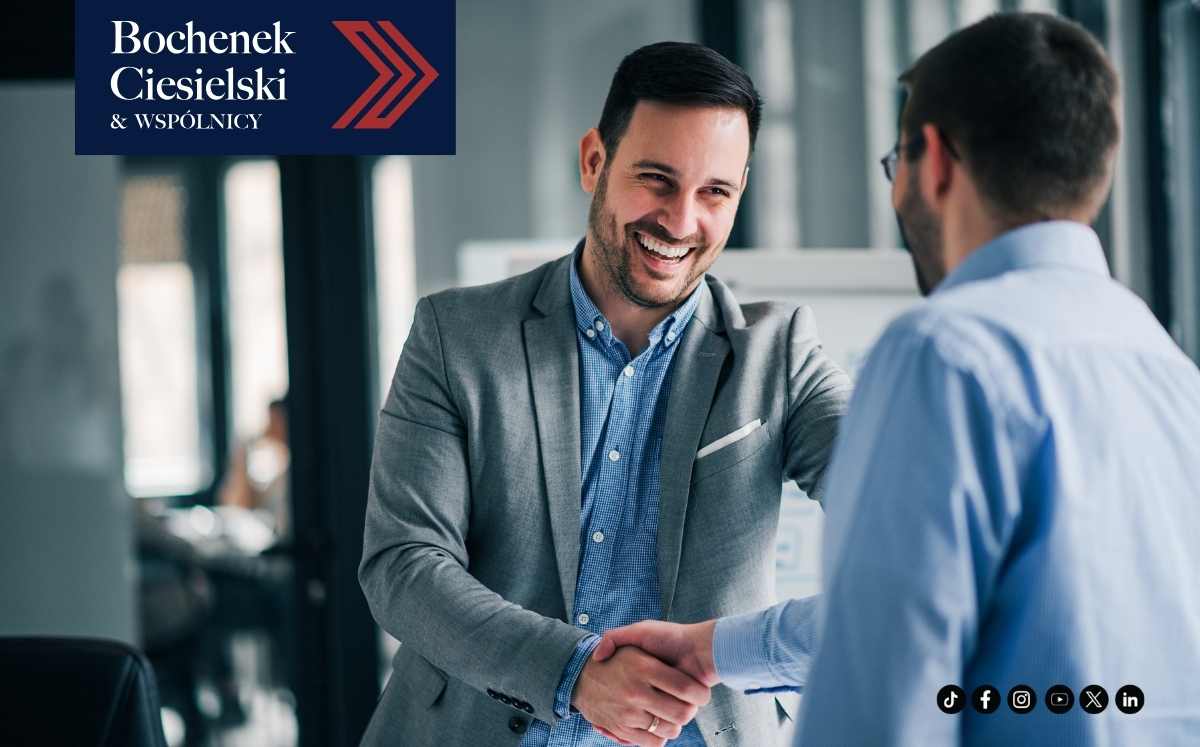 Dwóch uśmiechniętych mężczyzn w garniturach ściskających sobie dłonie, symbolizujące udaną współpracę i zadowolenie z rozwiązania problemu prawnego.