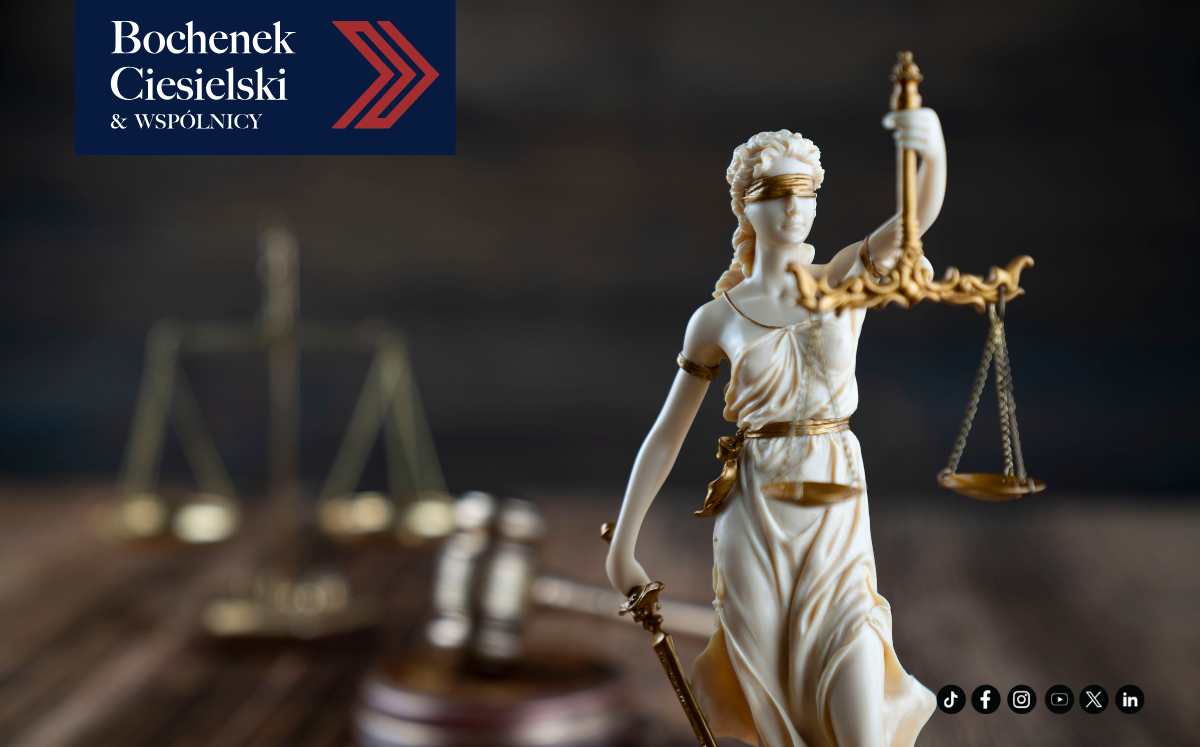 Figurka Temidy, symbol sprawiedliwości, z wagą i mieczem, na tle rozmytych dokumentów sądowych.