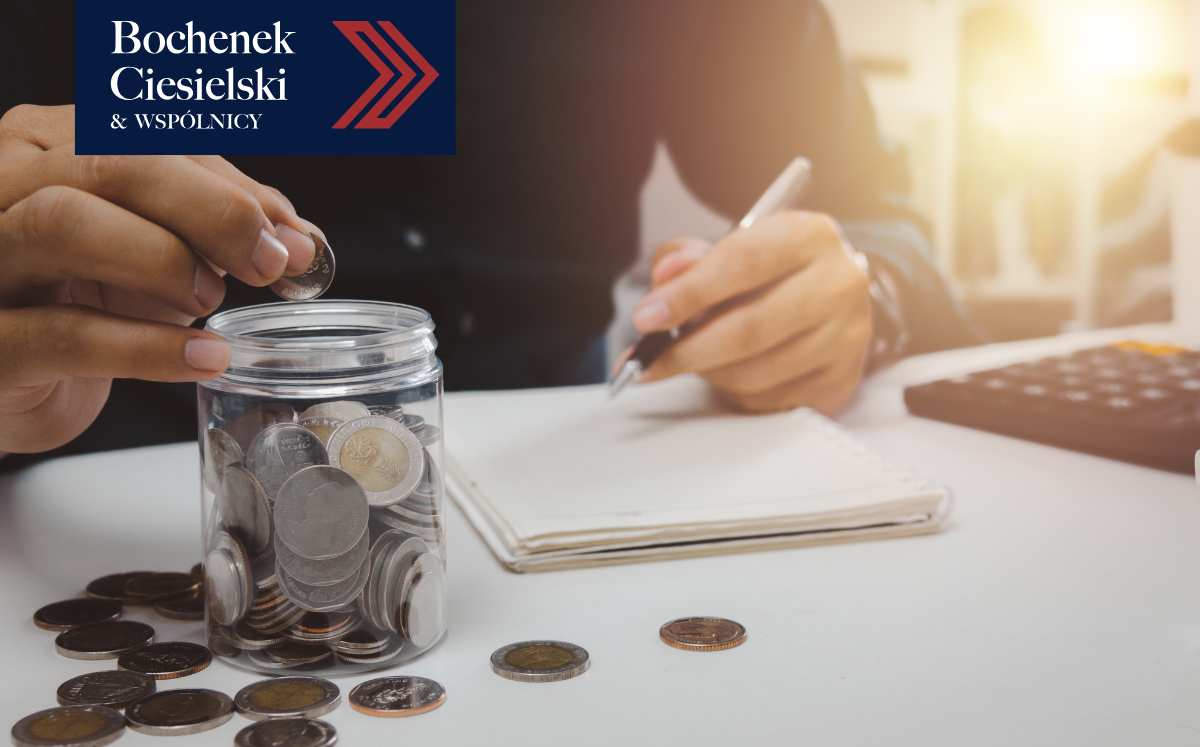 Osoba odkładająca monety do słoika, robiąca notatki finansowe.