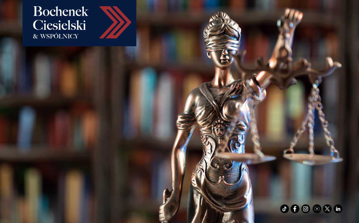 Posąg Temidy z zasłoniętymi oczami i wagą w dłoni na tle biblioteki prawniczej – symbol sprawiedliwości i procesu sądowego; logo kancelarii Bochenek Ciesielski & Wspólnicy.