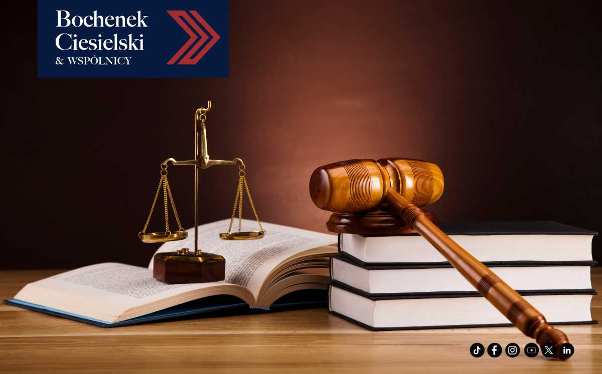 Kodeksy karne, młotek sędziowski i waga leżące na drewnianym biurku