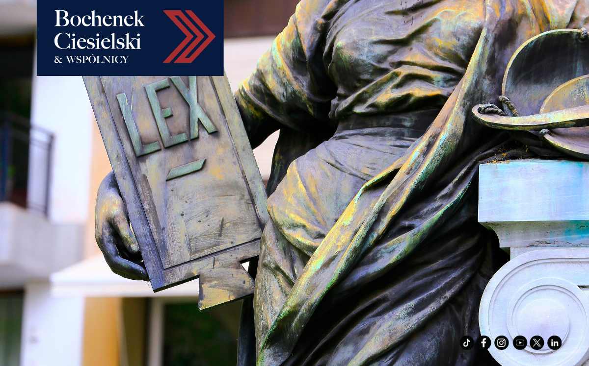 Fragment posągu przedstawiającego postać z tablicą z napisem „LEX”, symbolizujący prawo; w lewym górnym rogu widoczne logo kancelarii Bochenek Ciesielski & Wspólnicy.