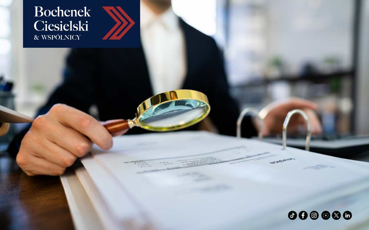 Osoba w garniturze analizująca dokumenty za pomocą lupy – audyt lub weryfikacja umowy.