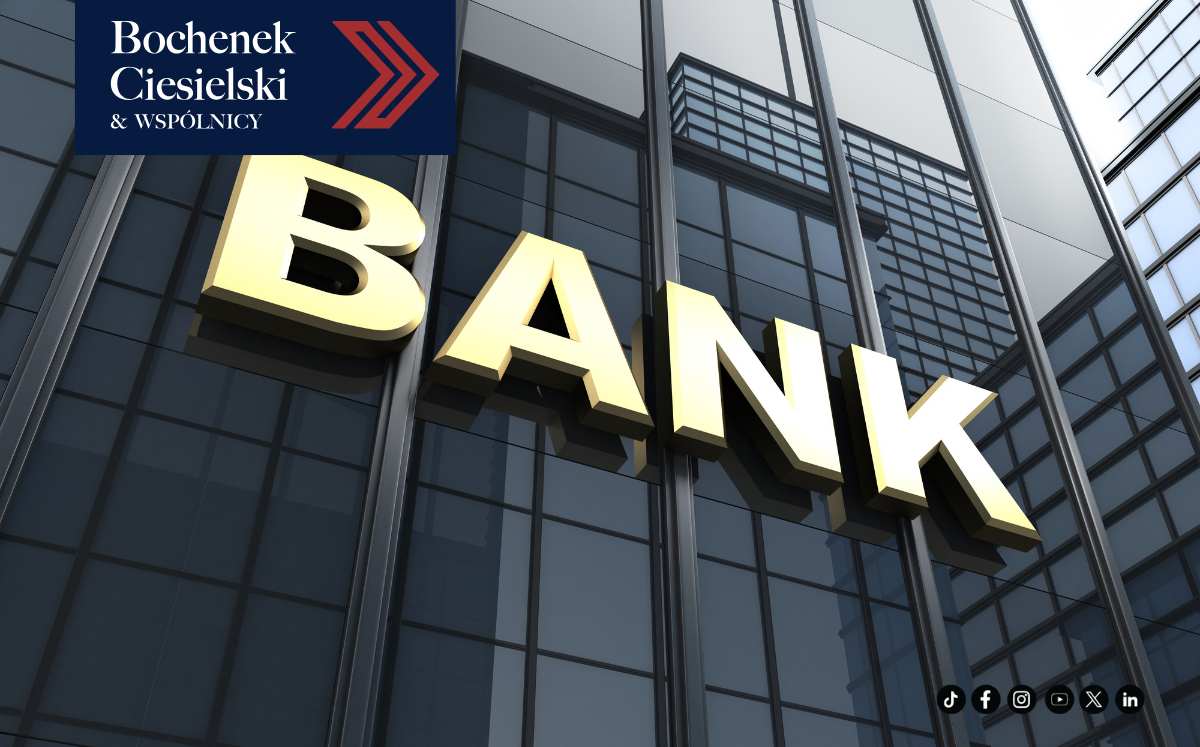Szklany budynek banku z dużym złotym napisem „BANK”, w lewym górnym rogu logo Bochenek Ciesielski & Wspólnicy.