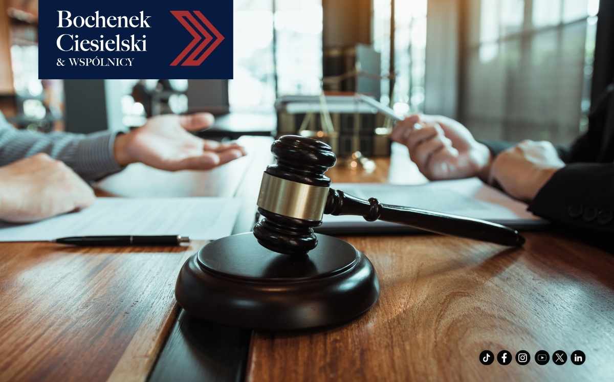 skd-a-sprawy-kredytobiorcow-w-sadzie Młotek sędziowski na sali sądowej, w tle dwie osoby omawiają dokumenty; w lewym górnym rogu logo kancelarii Bochenek Ciesielski & Wspólnicy.