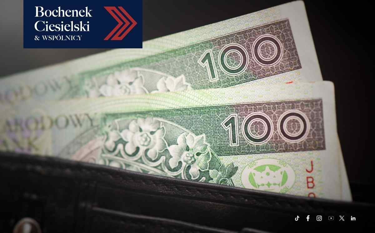 Banknoty 100 zł wystające z czarnego portfela, w lewym górnym rogu logo kancelarii Bochenek Ciesielski & Wspólnicy.