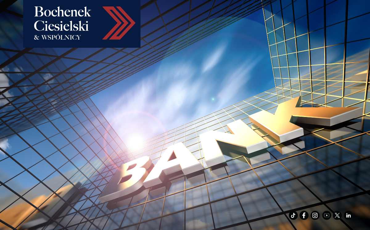 Szklany wieżowiec banku z dużym napisem „BANK” na tle nieba.