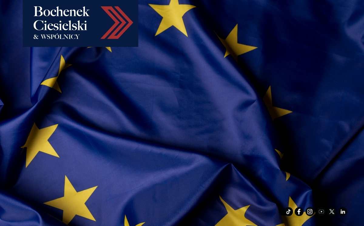 Flaga Unii Europejskiej z widocznymi złotymi gwiazdami na granatowym tle, w lewym górnym rogu logo Bochenek Ciesielski & Wspólnicy.