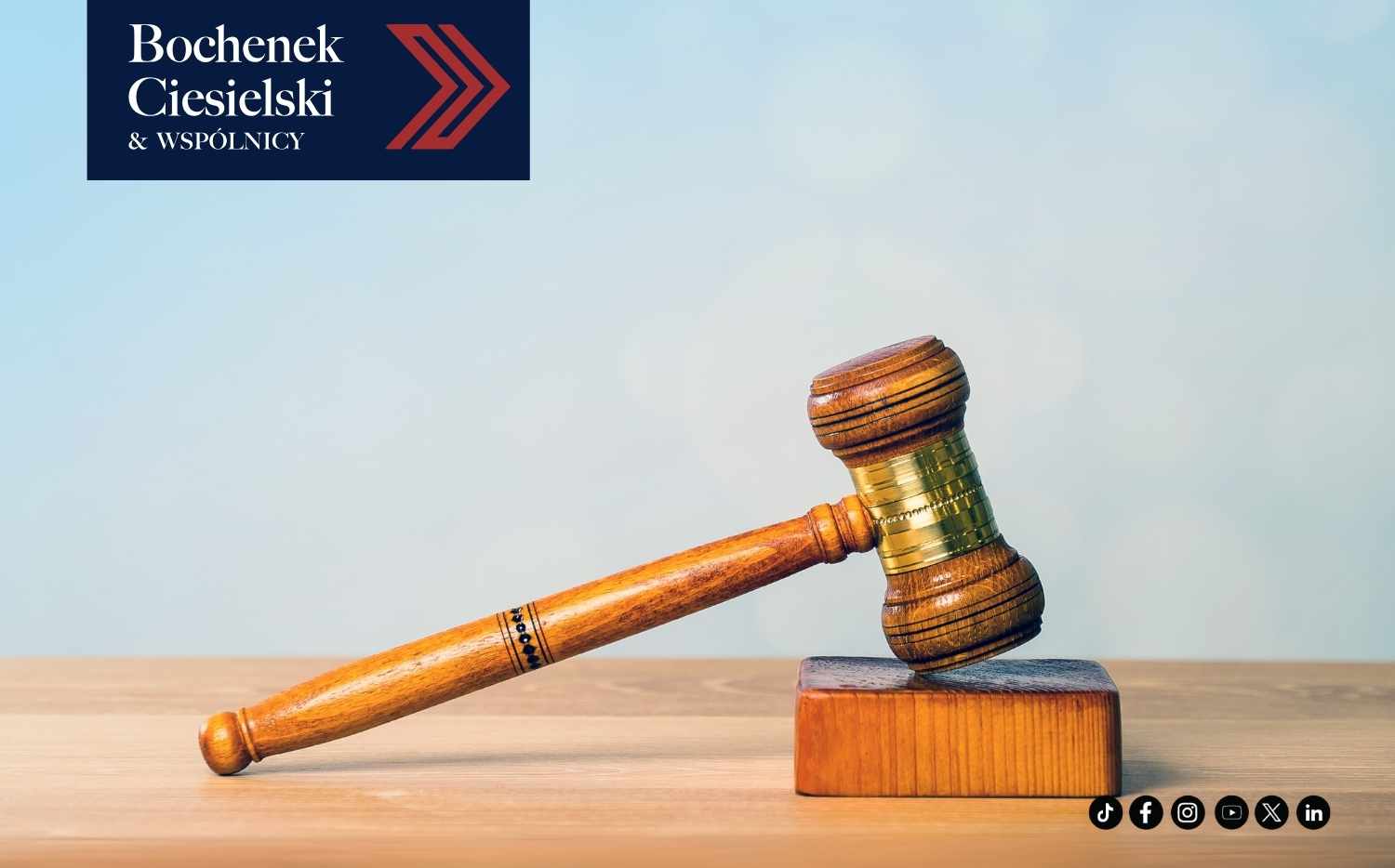 Drewniany młotek sędziowski na stole, symbol wymiaru sprawiedliwości, z logo kancelarii Bochenek Ciesielski & Wspólnicy w lewym górnym rogu.