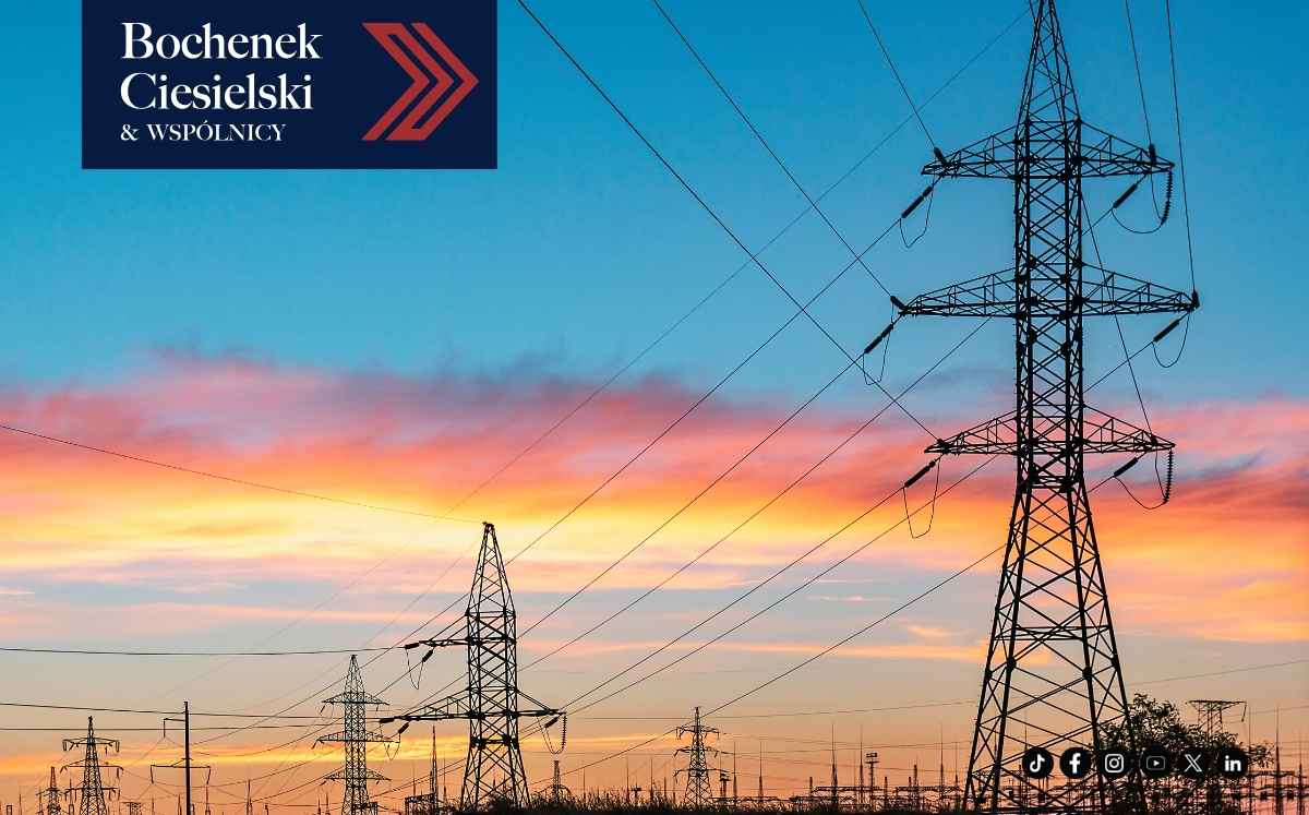 Linie wysokiego napięcia i słupy energetyczne na tle kolorowego zachodu słońca; w lewym górnym rogu widoczne logo „Bochenek Ciesielski & Wspólnicy”.