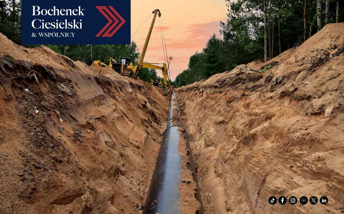 Rurociąg układany w głębokim wykopie otoczonym ziemią i lasem; w lewym górnym rogu znajduje się logo „Bochenek Ciesielski & Wspólnicy”.