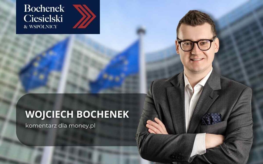Mężczyzna w garniturze z założonymi rękami na tle budynku instytucji Unii Europejskiej i flag UE, z widocznym logo kancelarii Bochenek Ciesielski & Wspólnicy.