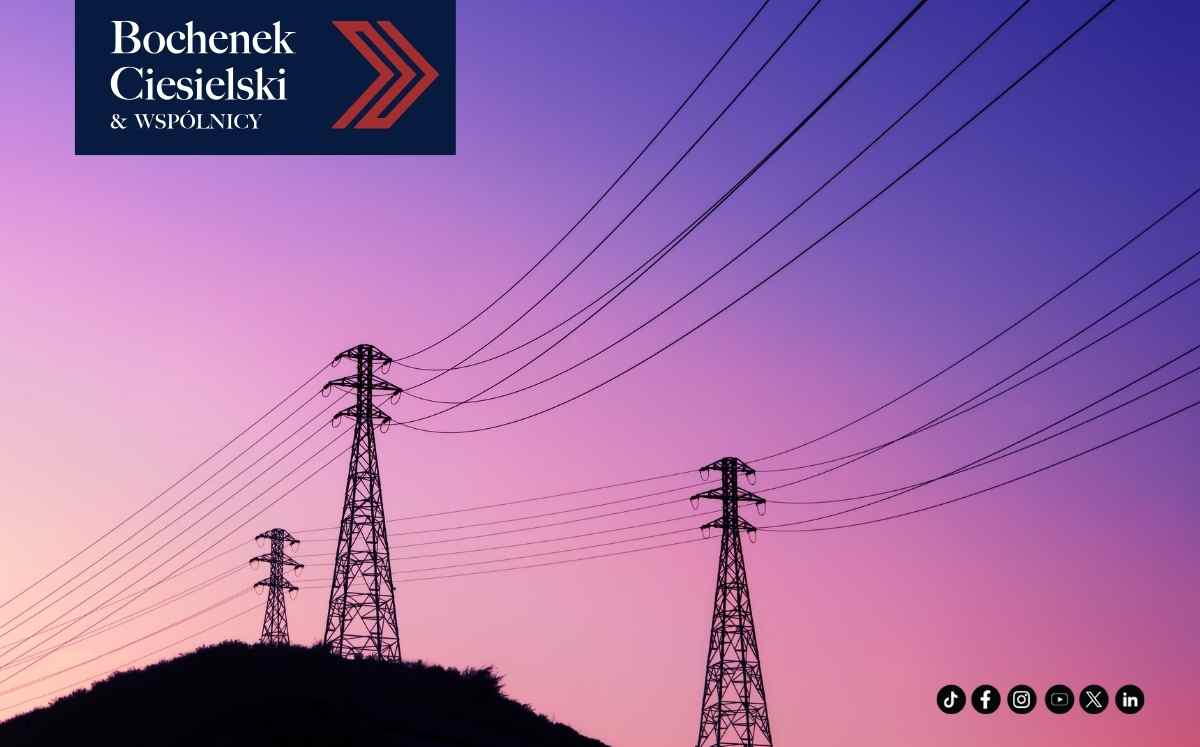 Słupy i linie wysokiego napięcia na tle różowo-fioletowego nieba o zmierzchu – infrastruktura energetyczna.
