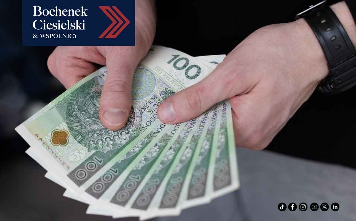 Dłonie trzymające plik banknotów 100 złotych – symbol rozliczeń finansowych i sporów konsumenckich.