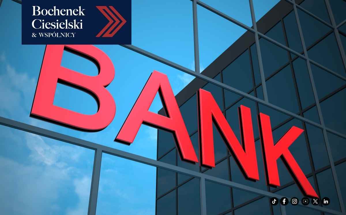Duży czerwony napis „BANK” na szklanej elewacji biurowca – symbol instytucji finansowej objętej postępowaniem upadłościowym.