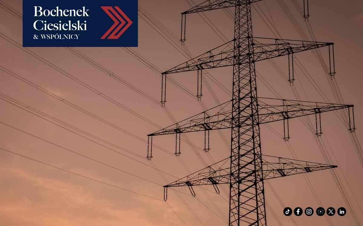 Słup wysokiego napięcia z liniami energetycznymi na tle zachodzącego słońca