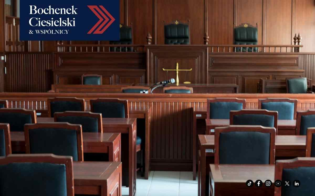 Drewniana sala sądowa z ławą sędziowską, mikrofonem i godłem Temidy w tle – symbol rozprawy