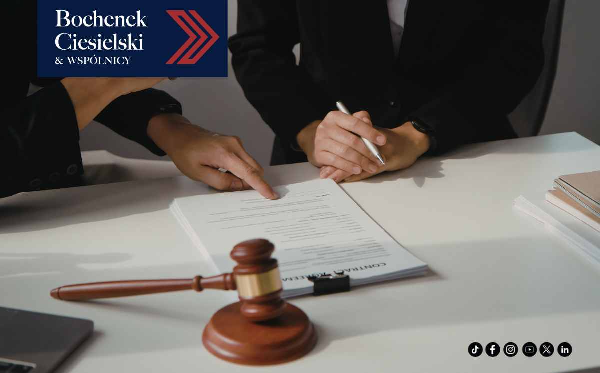 Prawnicy analizują i podpisują dokumenty przy biurku z widocznym młotkiem sędziowskim.