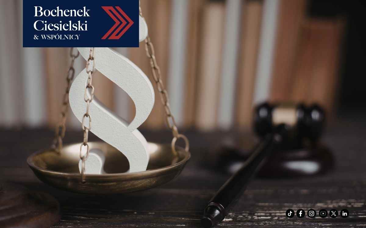 Symbol paragrafu na wadze sprawiedliwości obok młotka sędziowskiego – ilustracja zmian w prawie.