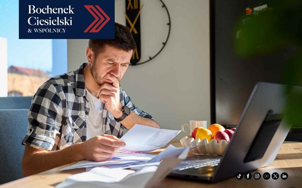 Mężczyzna analizuje dokumenty przy laptopie – frankowicz sprawdzający pismo od syndyka Getin Bank.