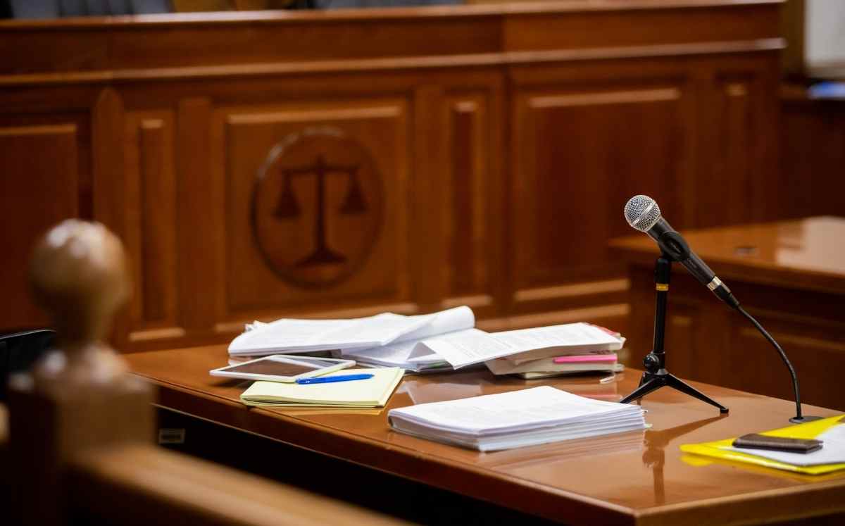 Sala sądowa z dokumentami i mikrofonem na stole podczas rozprawy sądowej dotyczącej sprawy frankowej