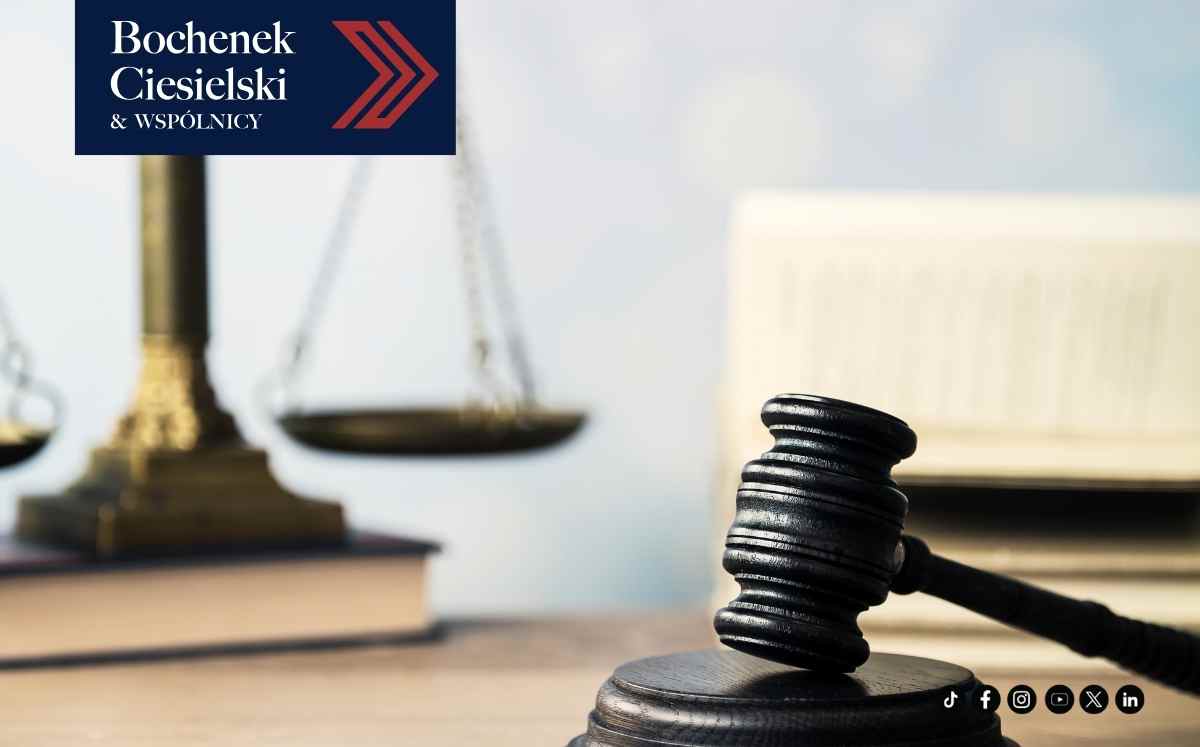 Młotek sędziowski na biurku na pierwszym planie, w tle waga sprawiedliwości i księgi prawnicze oraz logo kancelarii Bochenek, Ciesielski i Wspólnicy.