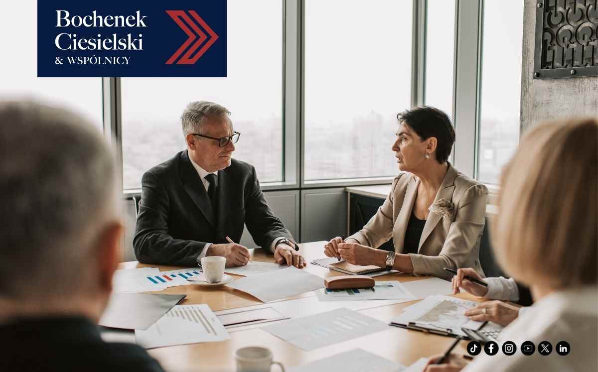 Spotkanie prawników i klientów przy stole konferencyjnym z dokumentami.