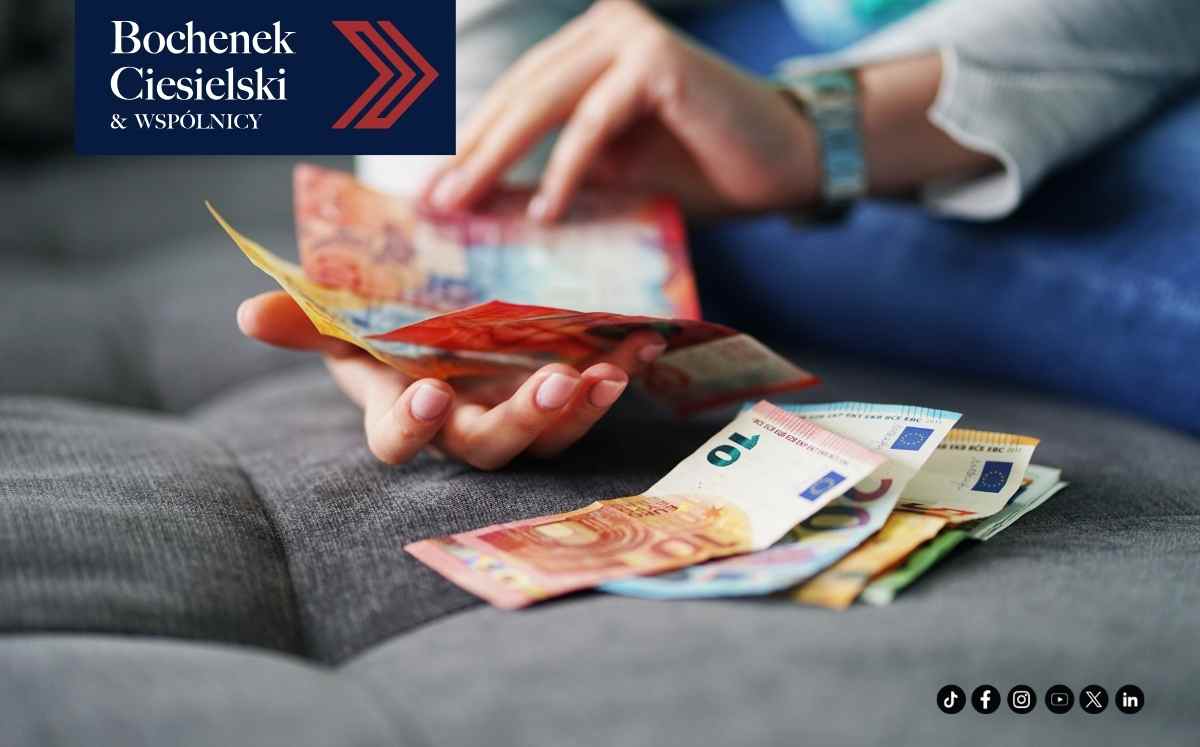 Osoba liczy banknoty euro siedząc na kanapie, w lewym górnym rogu widoczne logo kancelarii Bochenek, Ciesielski i Wspólnicy.
