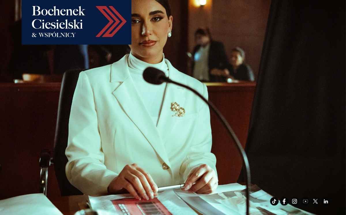 Kobieta w białym garniturze zeznająca przy mikrofonie na sali sądowej.