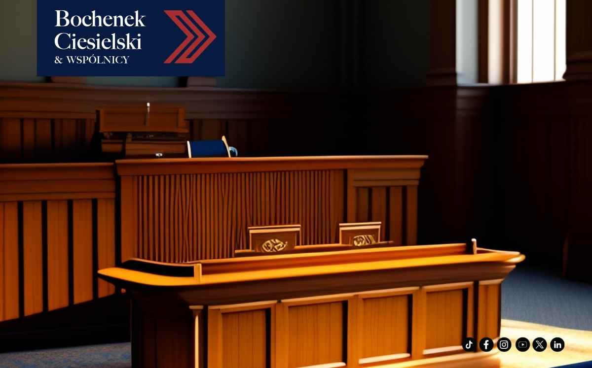 Sala rozpraw sądowych z drewnianą ławą sędziowską i miejscem dla świadków, symbolizująca wymiar sprawiedliwości.