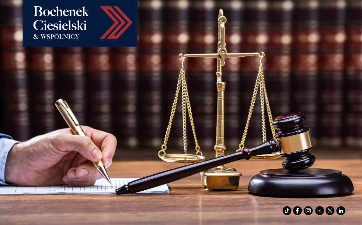 Prawnik podpisujący dokumenty obok wagi szali i młotka sędziowskiego