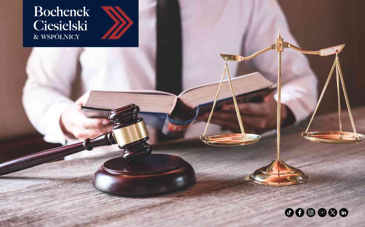 Prawnik w białej koszuli czytający grubą księgę obok wagi szali i młotka sędziowskiego