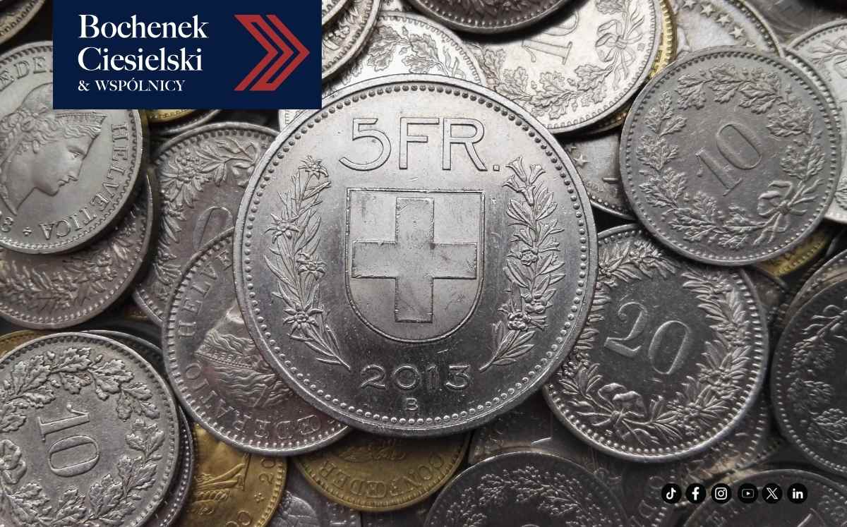 Stos szwajcarskich monet z widoczną monetą 5 franków na pierwszym planie oraz logo kancelarii Bochenek Ciesielski & Wspólnicy.