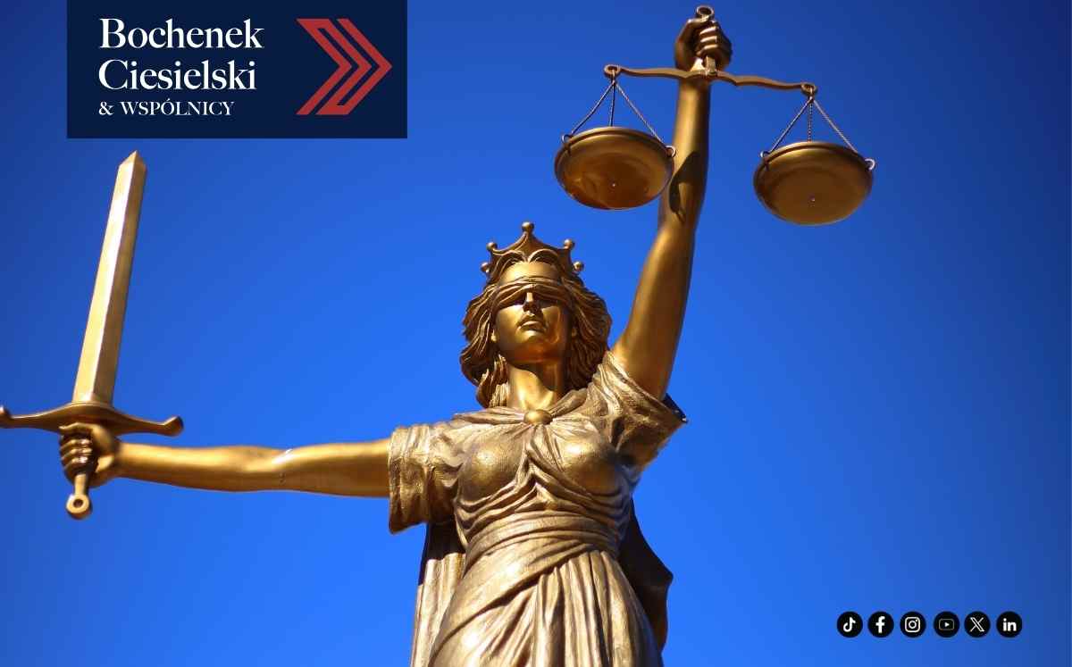 Złota figura Temidy z wagą i mieczem na tle błękitnego nieba, z logo Bochenek Ciesielski & Wspólnicy.