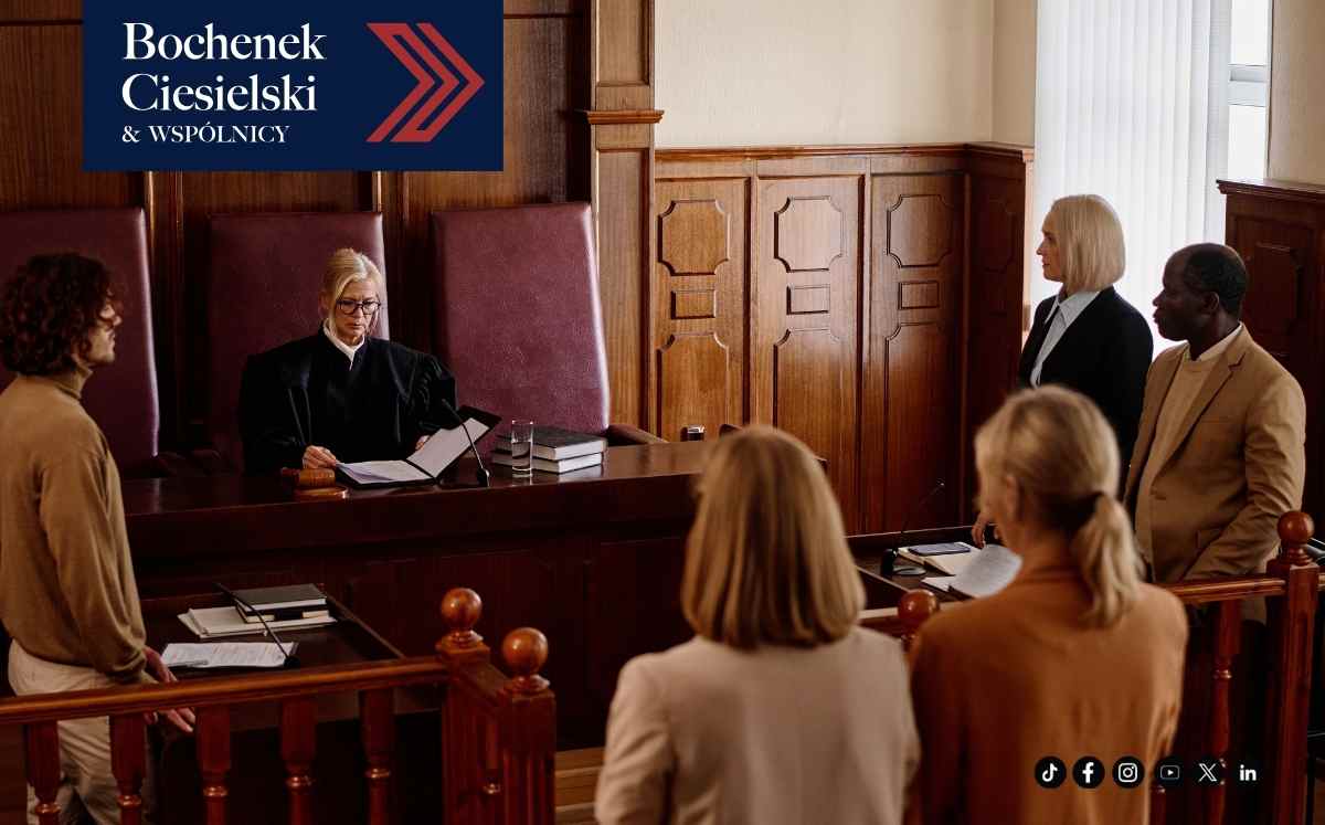 Sala sądowa podczas rozprawy z udziałem sędziego, stron postępowania i pełnomocników.