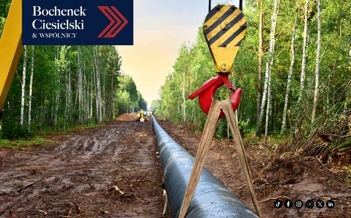 Budowa gazociągu na działce z widoczną rurą przesyłową i sprzętem budowlanym w tle.