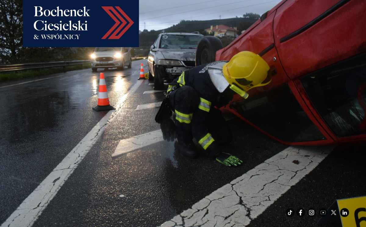 Strażak zabezpieczający miejsce wypadku drogowego z przewróconym samochodem na mokrej jezdni