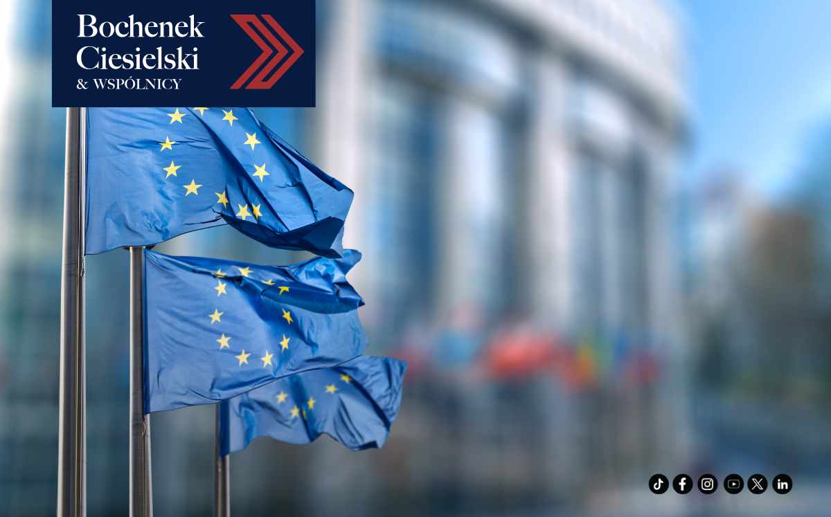 Flagi Unii Europejskiej przed budynkiem instytucji UE i logo kancelarii