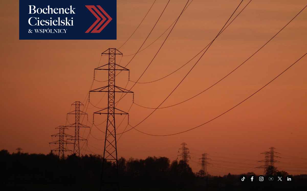 Linie energetyczne przebiegające nad działką na tle zachodu słońca