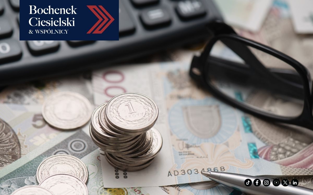 Na biurku leżące banknoty, kalkulator, okulary i monety (pln)