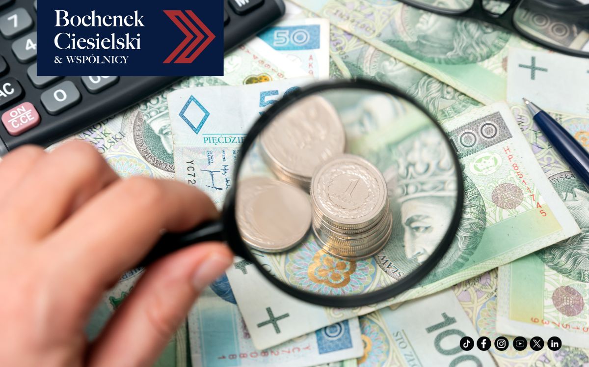Obrazek przedstawia banknoty i monety. Widać dłoń trzymającą lupę