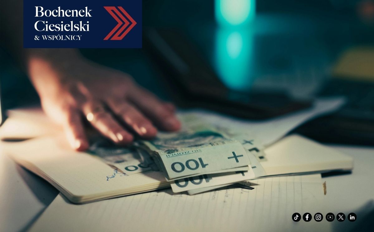 Zbliżenie na rękę kładącą banknoty na otwarte notesy