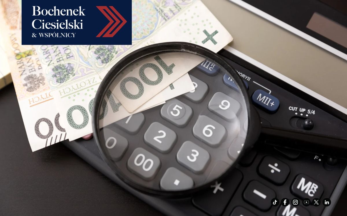 Zbliżenie na lupę leżącą na kalkulatorze i polskich banknotach. 
